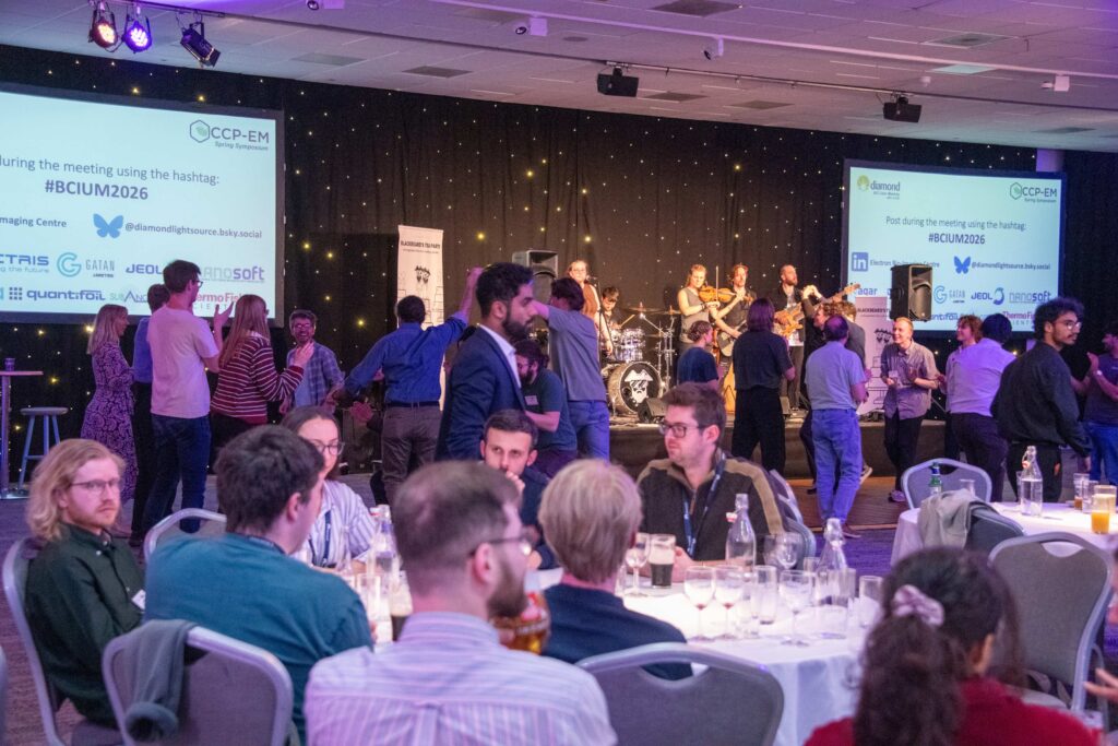 Delegates dancing in Ceilidh with band in background and delegates seated at tables in the foreground